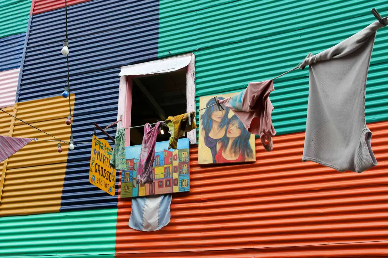 A window in a colourful wall with art and a faux clothes line