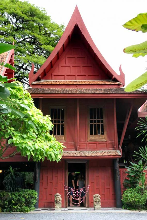 Traditional Thai architecture in red, surrounded by lush landscaping