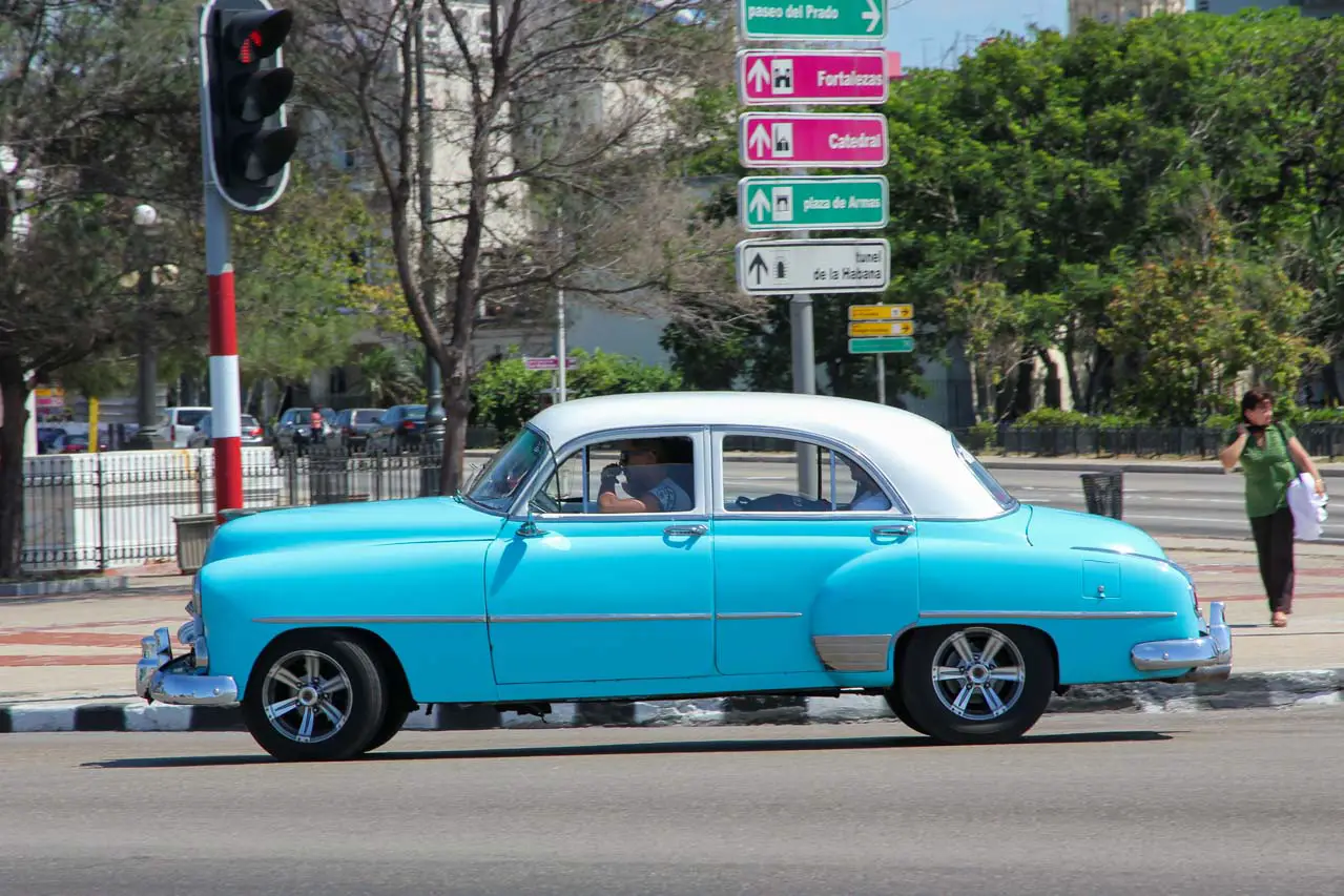 Aqua and white classic car driving through intersection