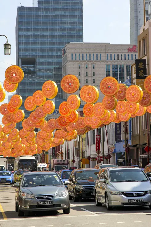 Coin-shaped lanterns hanging over traffic in Chinatown street
