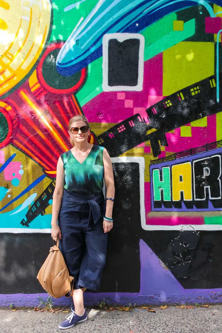 Woman leaning against colourful mural in Harlem