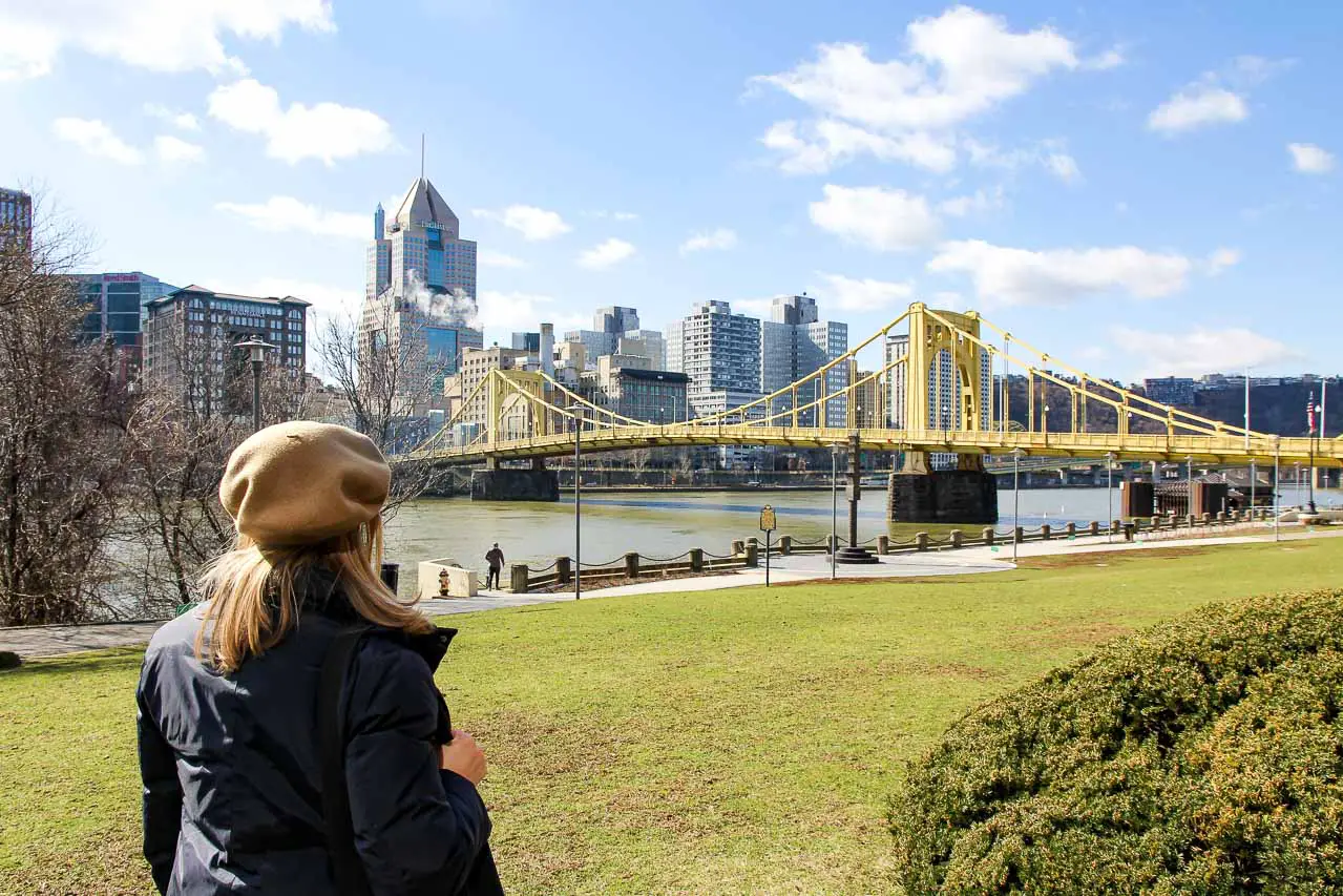 Woman looking at a yellow bridge with city skyscrapers in background
