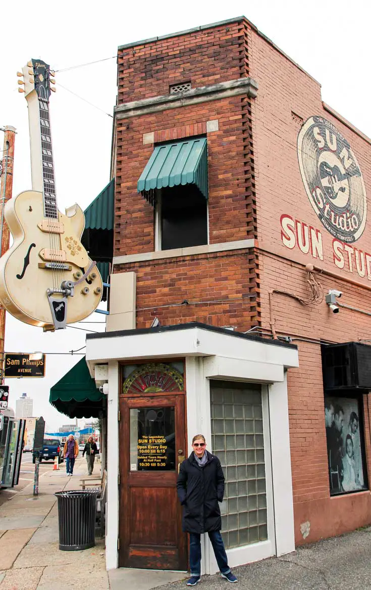 Woman standing at the front of corner block with guitar signage