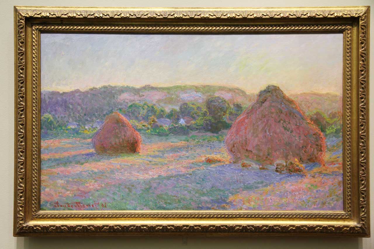 Impressionist painting of wheat stacks in gold frame