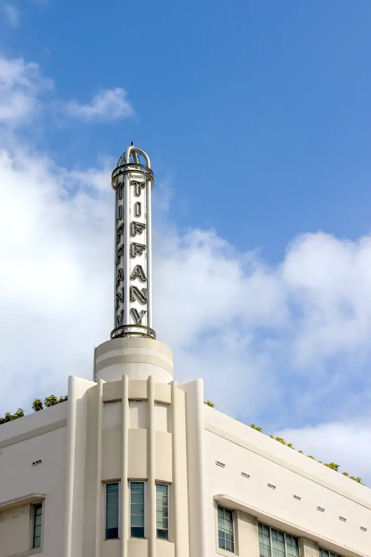 Art deco spire on corner of building with "Tiffany" in neon