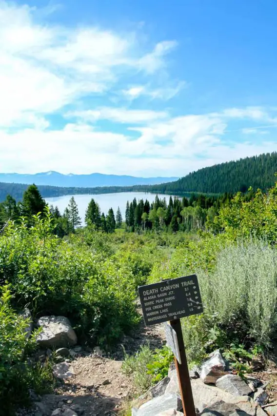 Trail sign for Death Canyon with Lake and mountains in the background