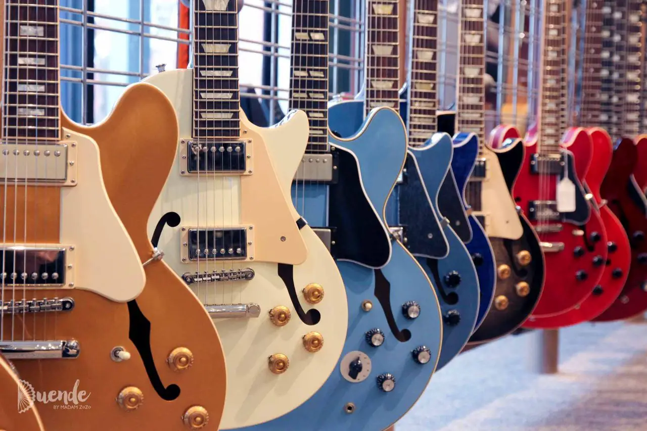 Line up of guitars in cream, blue and red, inside the Gibson Guitar Factory