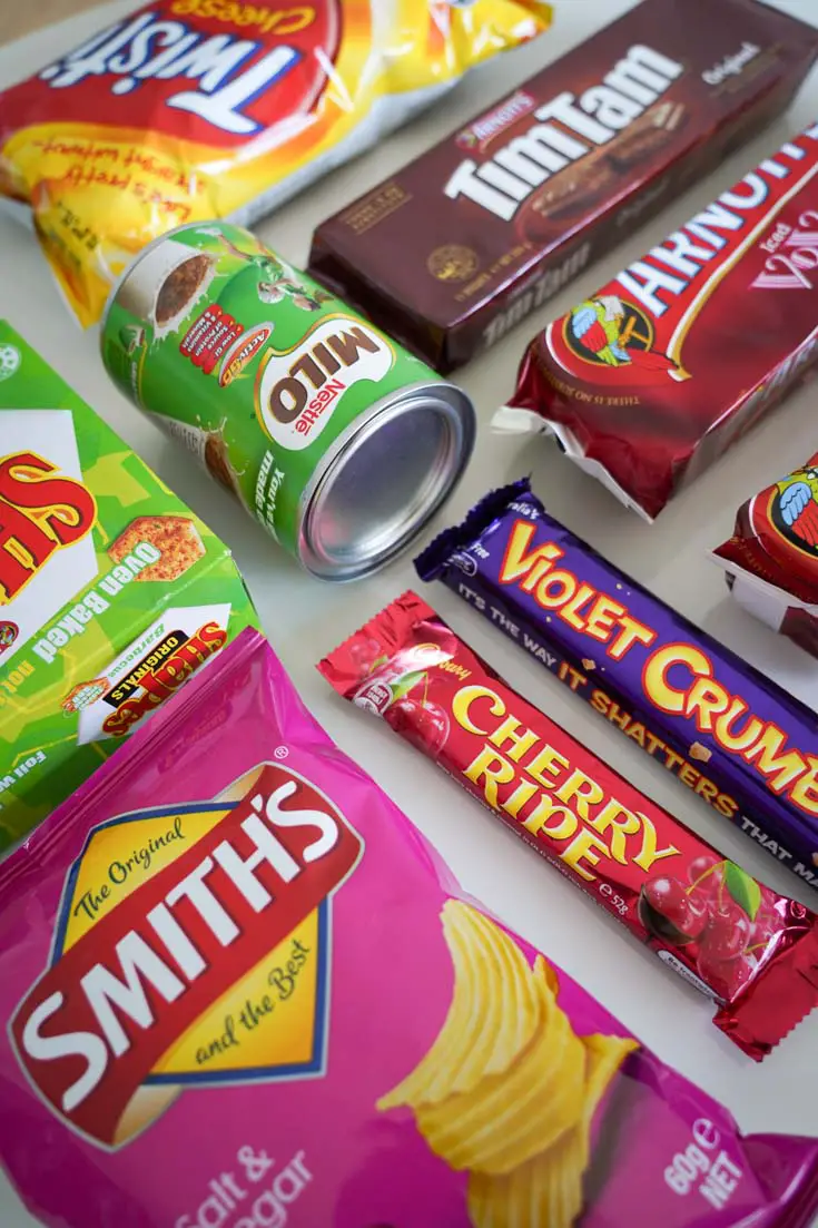 Uniquely Australian snacks and treats including a can of Milo, Tim Tams and a Smiths chips and a Cherry Ripe