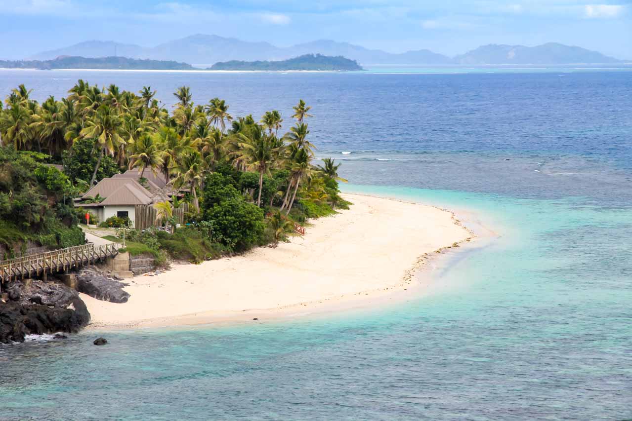 Sandy island with palm trees and buildings