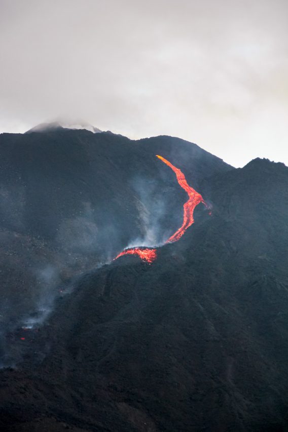 A fresh, red hot, lava flow pouring down the black lava beneath