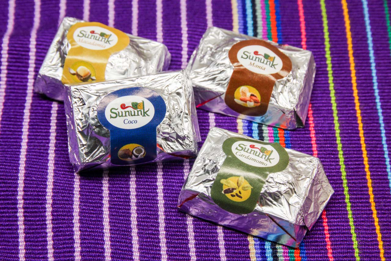 Flavoured chocolates in silver wrappers sitting on a traditionally woven textile in purple with coloured stripes