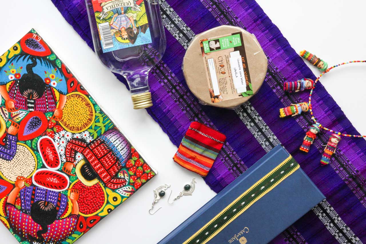 Flat lay of souvenirs from Guatemala including textiles, chocolate, rum, jade and silver earrings, artwork and worry dolls