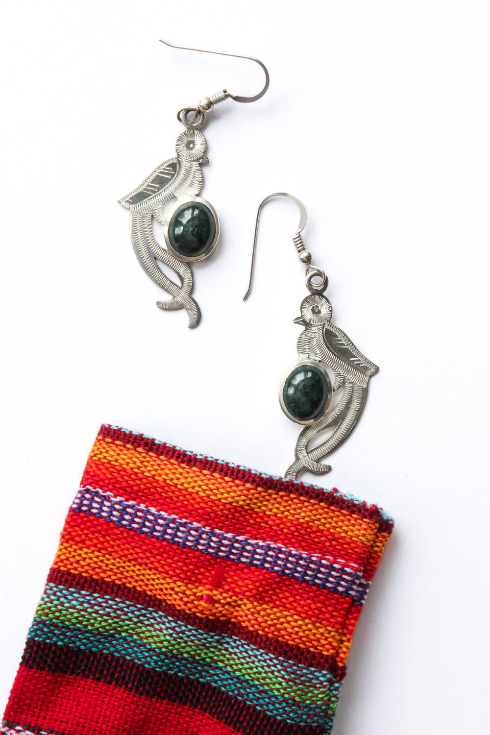Image of Quetzal shaped silver earrings with Jade stone, and a colourful woven pouch