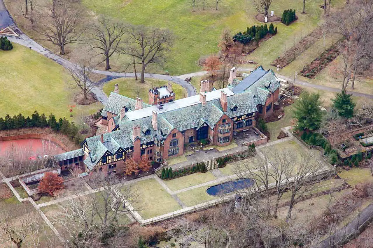 Aerial photo of large Tudor Revival mansion and gardens in early spring