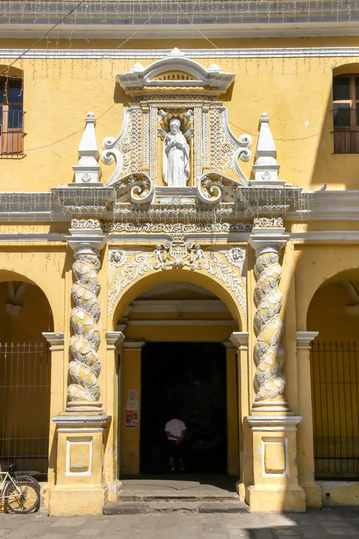 Entrance of yellow and white church with twisting columns framing arched doorway