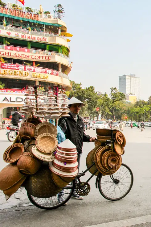 Man selling conical hats from a bicycle