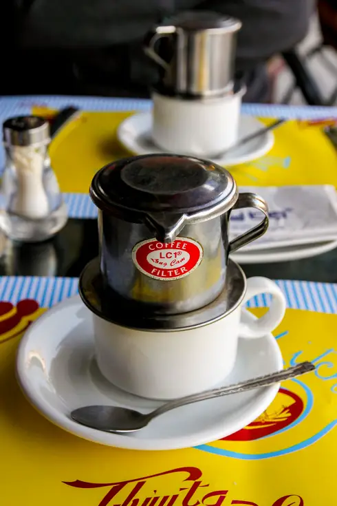 Vietnamese drip coffee on cafe table with yellow placemat