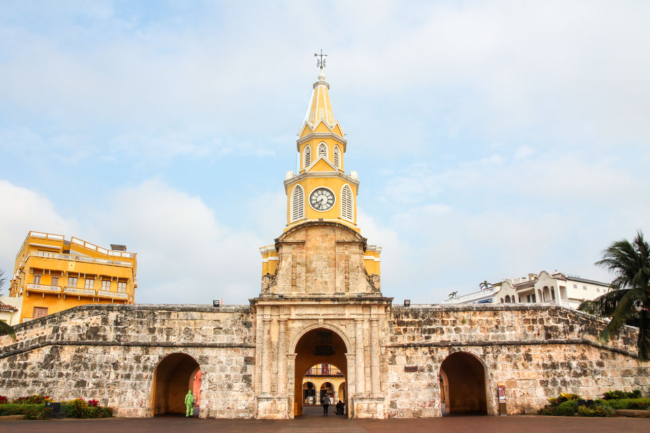 Stone wall with arched entrances, and a yellow and white clocktower