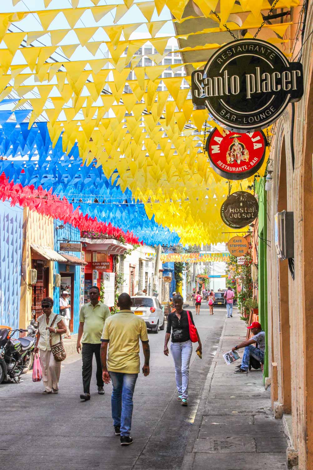 Pedestrian street lined in restaurants and bars with bunting flying overhead in the Colombian national colours