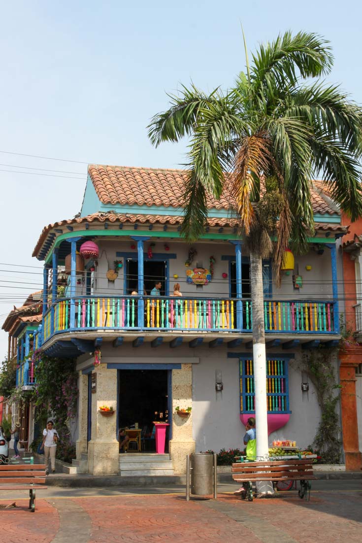 A colourful two-story restaurant with palm tree in Getsemani