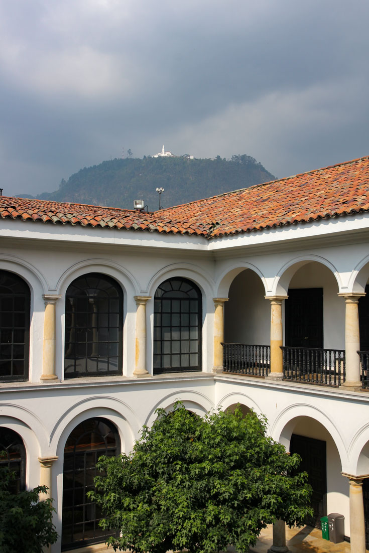 Image of arched colonade of two-story museum with mountaintop in background