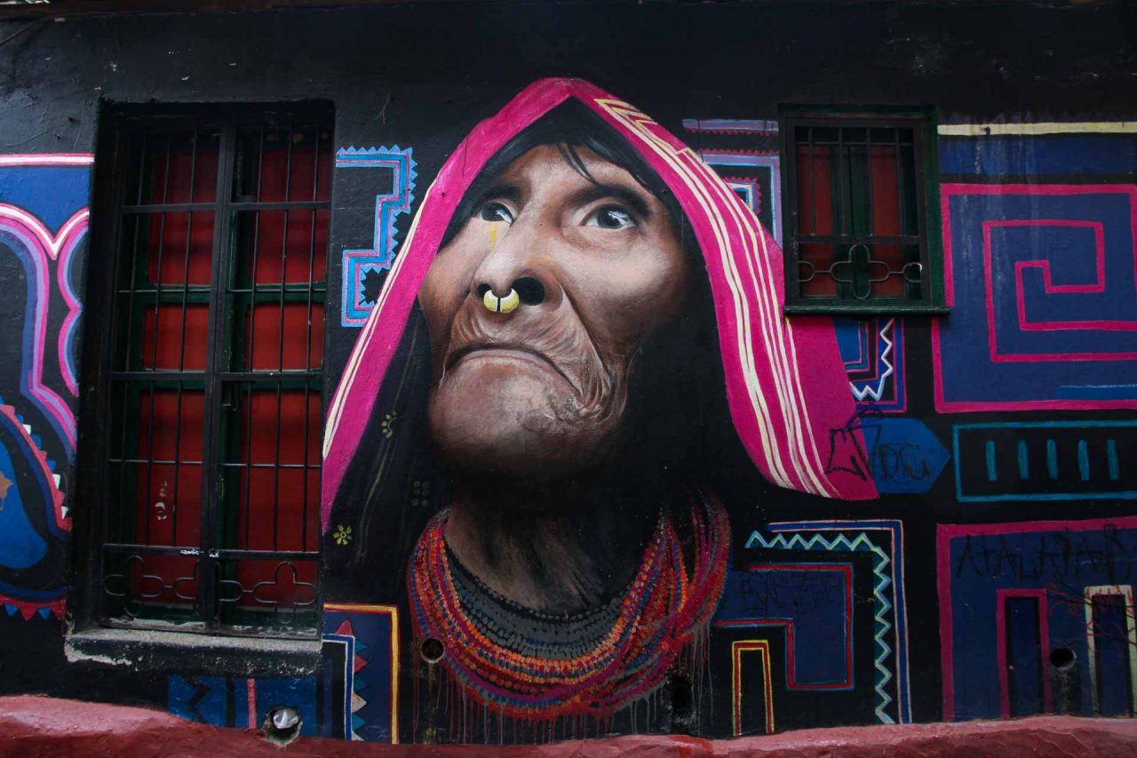 Wayuu woman in pink headdress and traditional jewellery painted on black wall