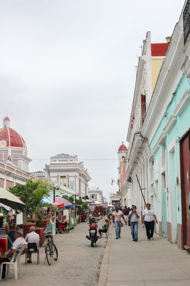 Pedestrians walking down sidewalk in Cienfuegos' historic downtown