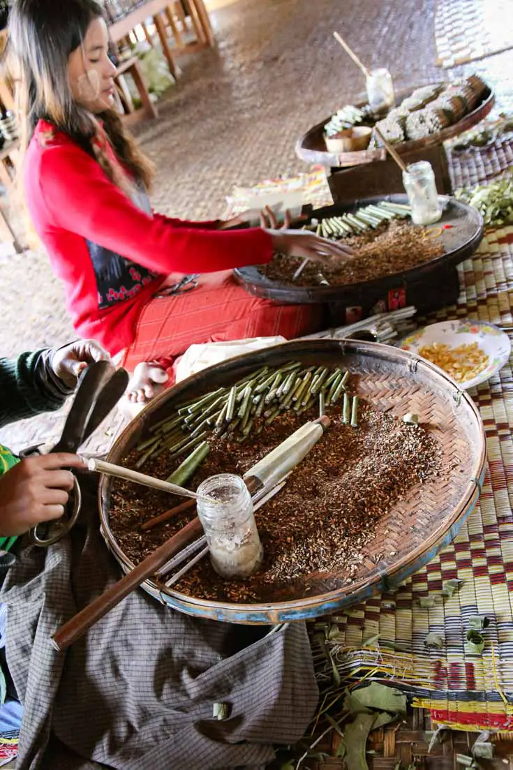 Women hand rolling cigars with ingredients in large baskets