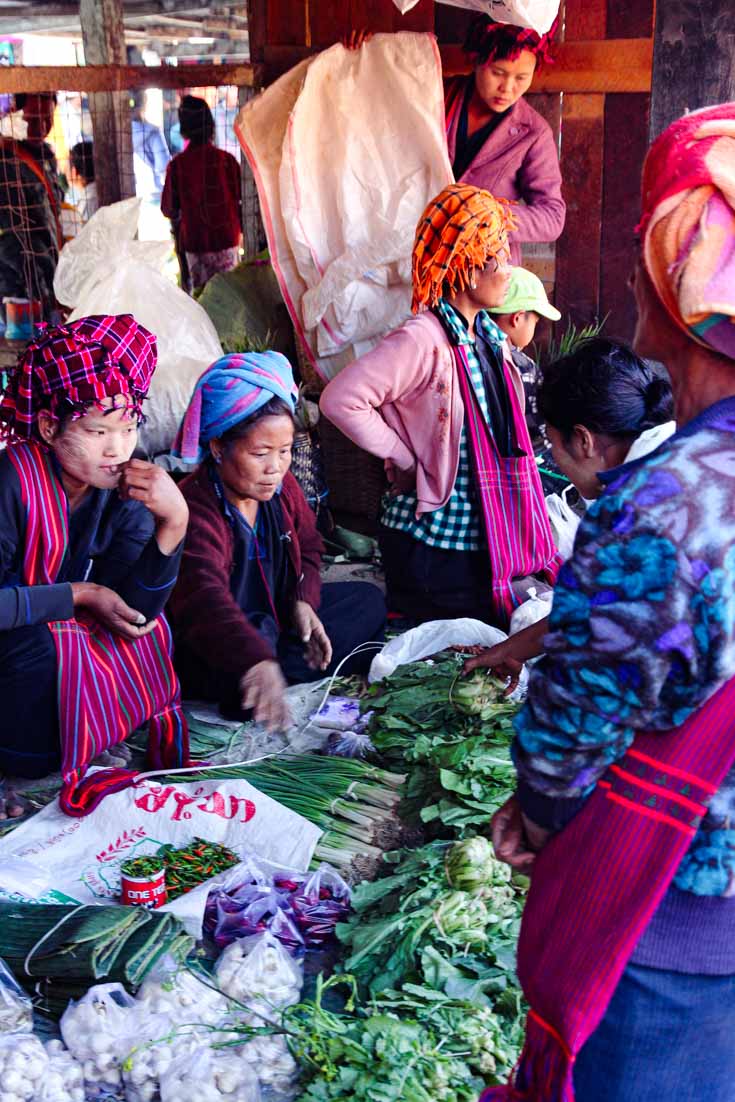 People in traditional dress selling and shopping fresh produce at rotating market