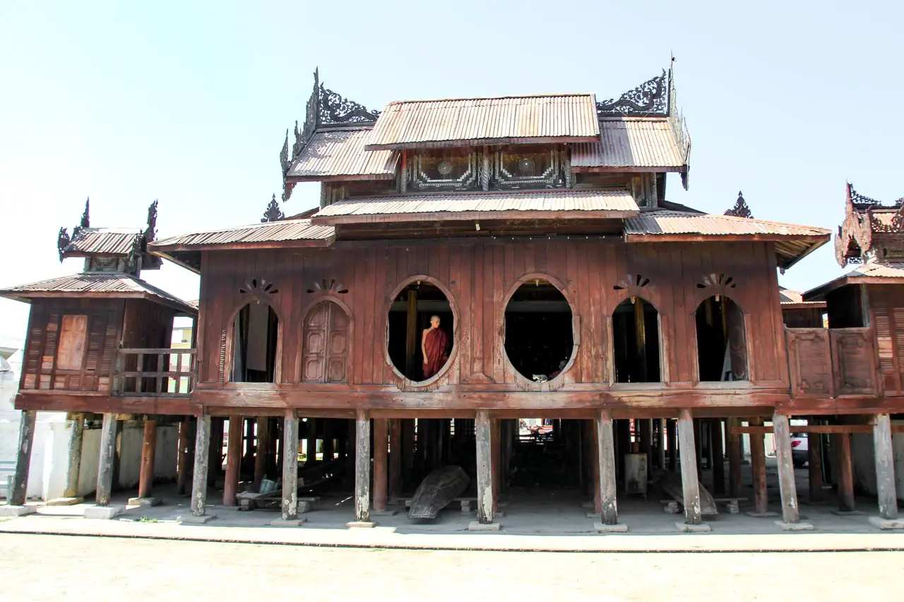 Shwe Yan Pyay monastery exterior - teak building on stilts with oval and arched windows and decorative elements on roof