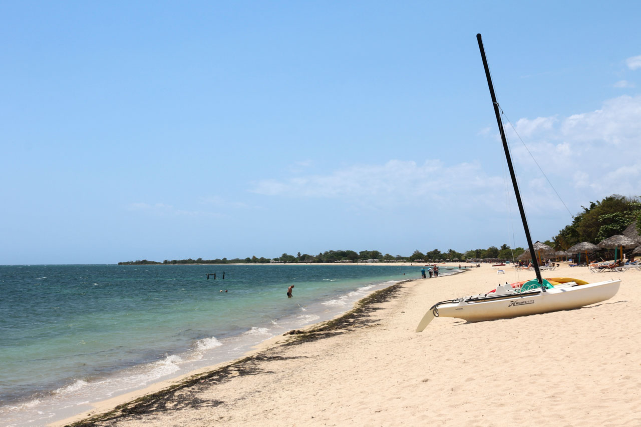 Beach with distant building and sailing boat on the sand