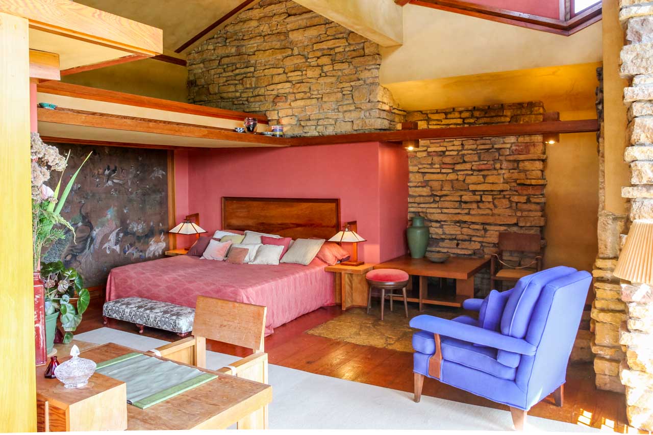 Taliesin main bedroom with dusky pink bed suite and blue armchair