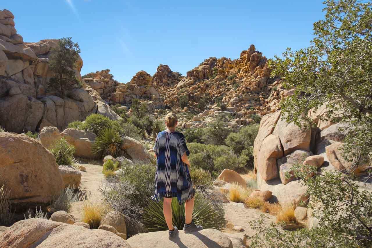 Woman looking out over small desert Valley framed with rock formations