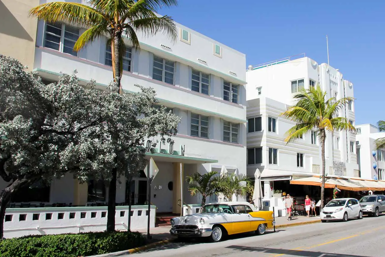White-washed art deco hotels with palm trees and a vintage car
