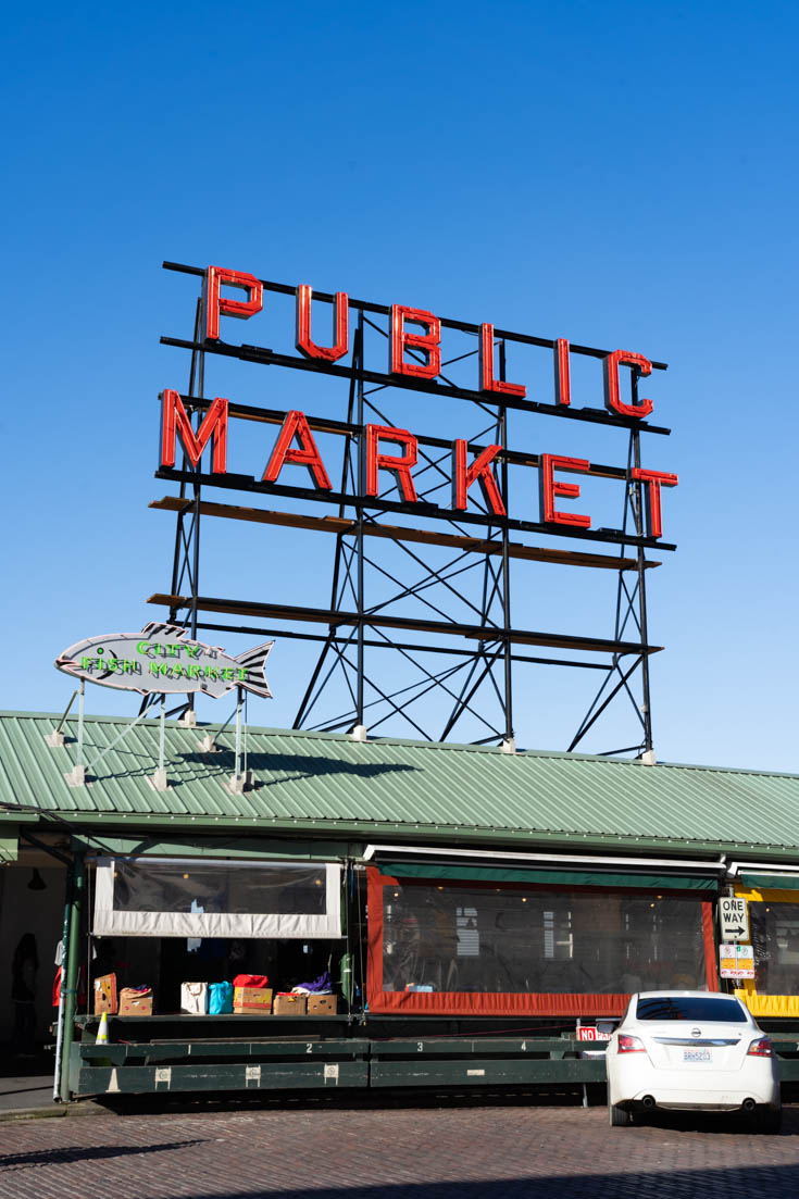 Pike Place Market viewed from the street with red "Public Market" sign against blue sky