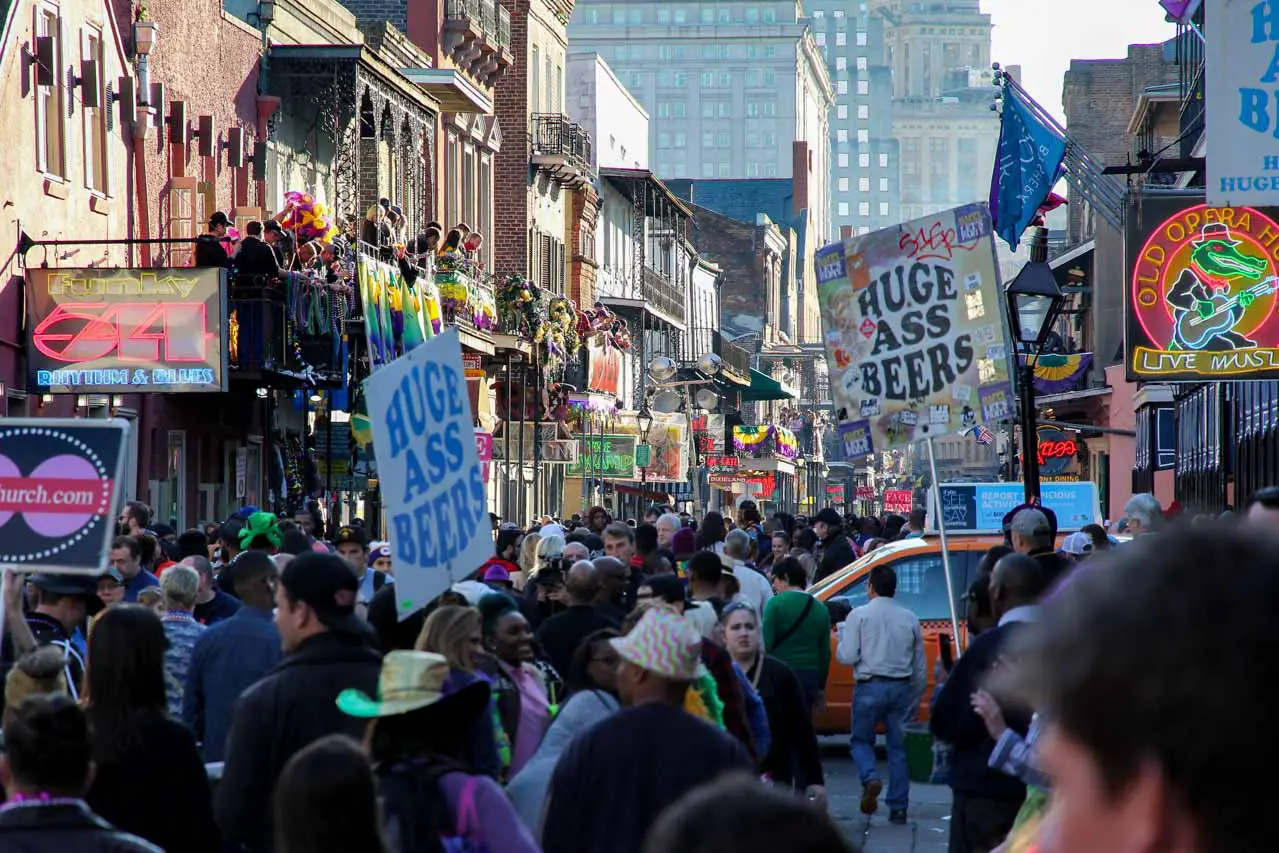 Crowds in Bourbon street with signs saying "Huge Ass Beers"