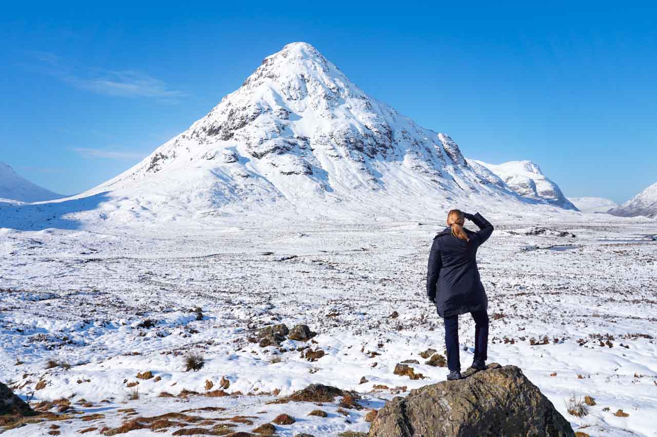 Woman standing on rock looking out at snowy peak