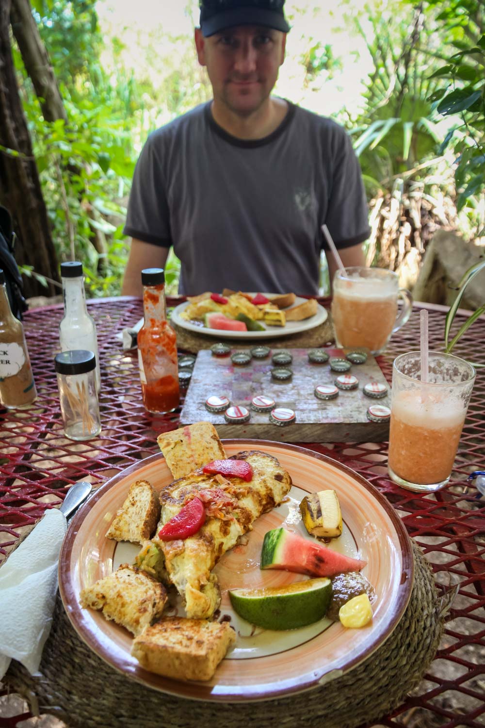 Man sitting across table with fruit smoothies, omelettes and a chess board