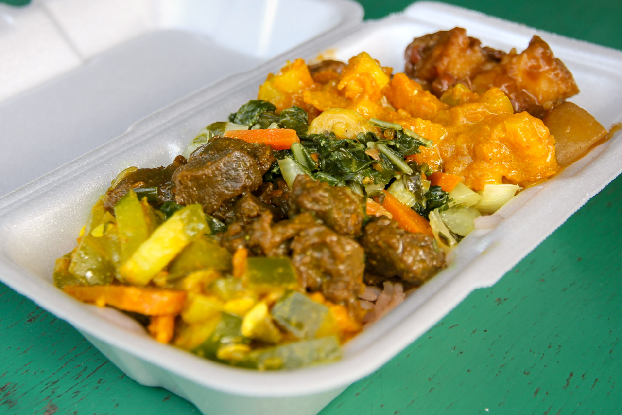 A sampling of Ital dishes in a white polystyrene container on the green bar at Ras Rody