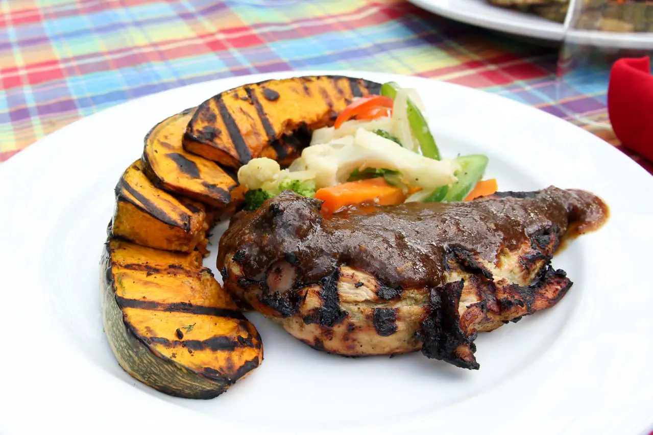 Jerk Chicken and grilled vegetables served on white plate at Jake's Treasure Beach, one of the best places to eat in Jamaica