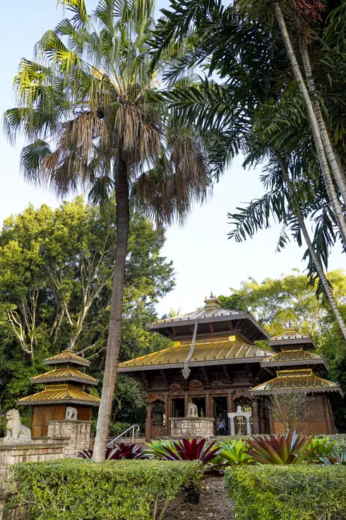 Pagoda with gold roof surrounded by garden including palm trees