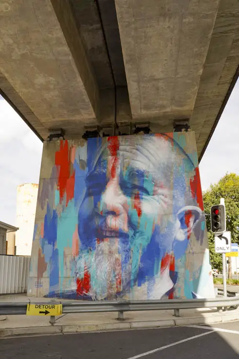 Mural of man with coloured overlay on pillar under railway bridge