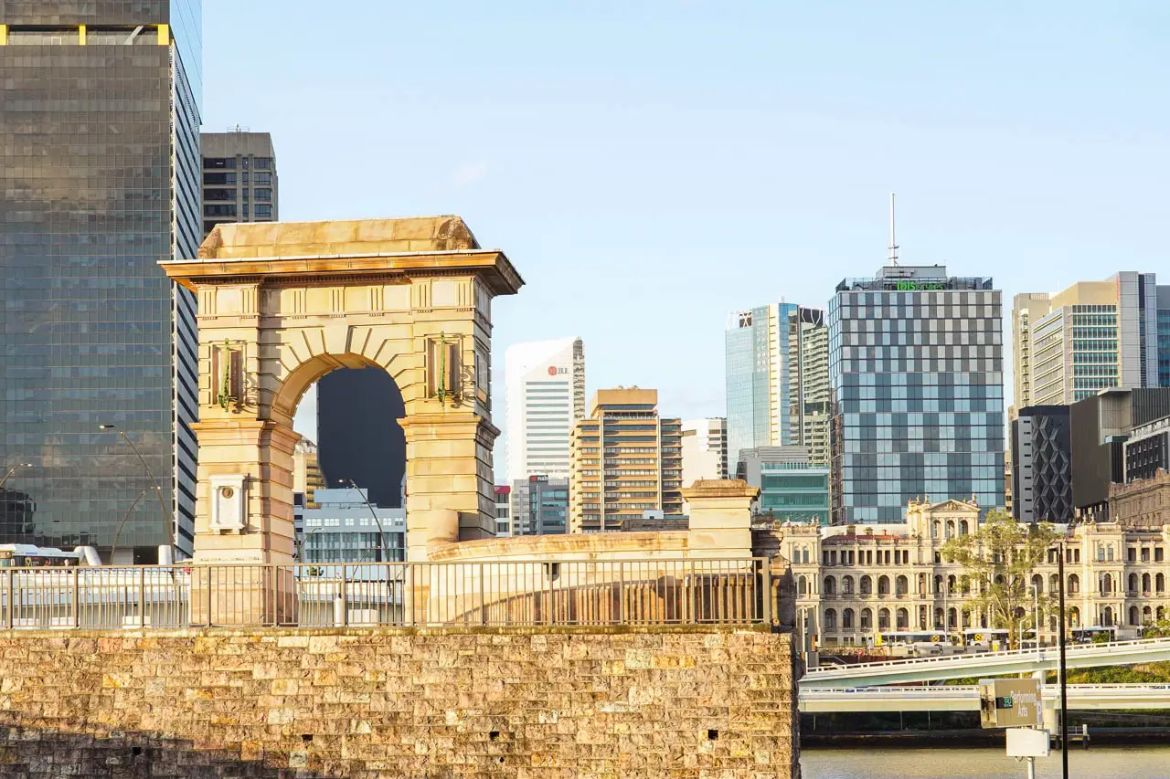 Standalone archway, remnant of a historic bridge against a modern city skyline