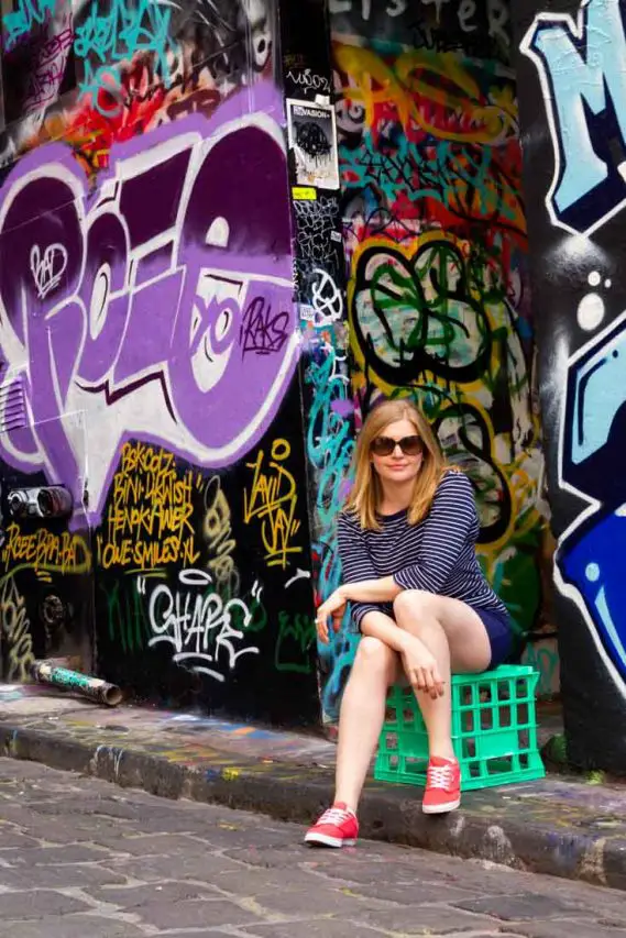 Madam ZoZo sitting on green milk crate with street art behind