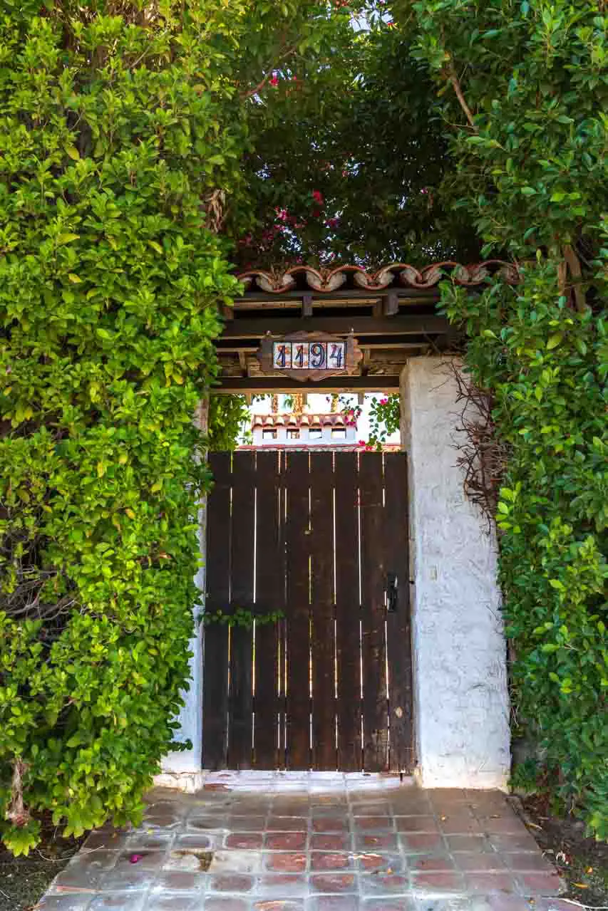 Spanish Colonial front gate surrounded by hedging