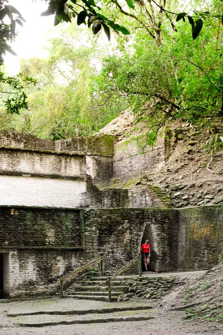 Woman in orange shirt looking out from doorway in Maya ruins