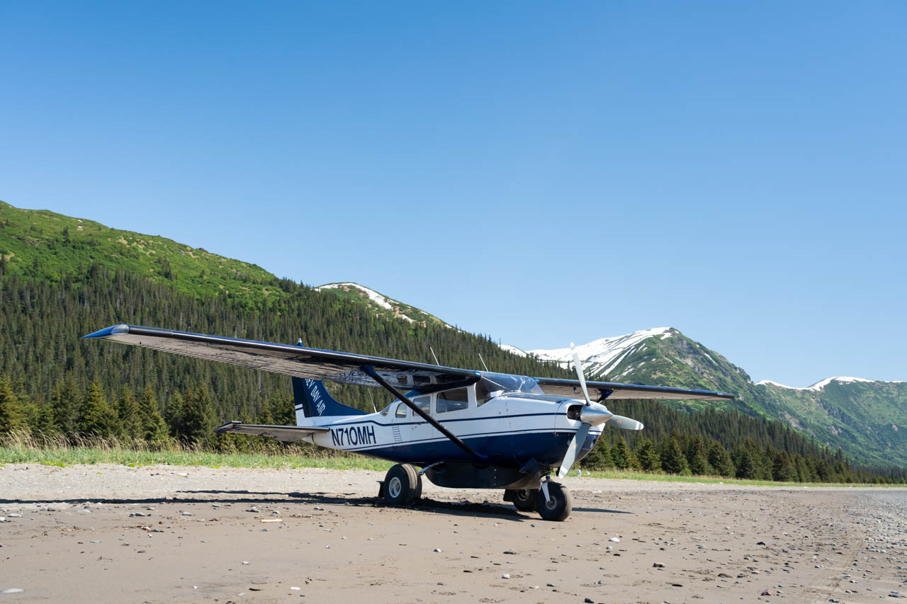 Small plane on a beach with mountains in the background