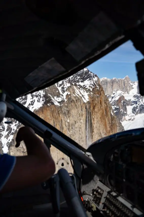 Pilot pointing out plane window to an avalanche in progress