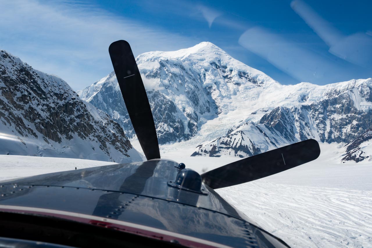 View from cockpit landing on glacier with large mountain peak in the distance