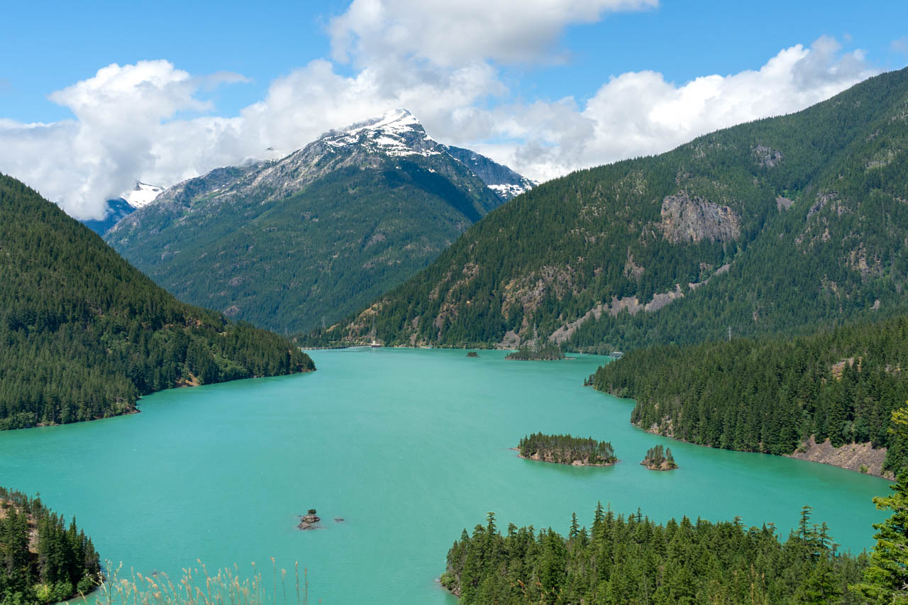 View over a turquoise mountain lake with cloud shrouded peak in the background